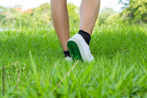 Foot in sneaker with step on foreground grassland