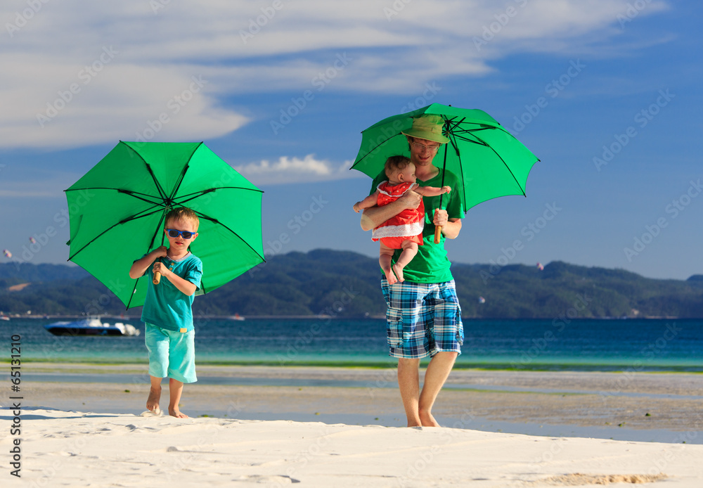 family with umbrellas on tropical beach vacation