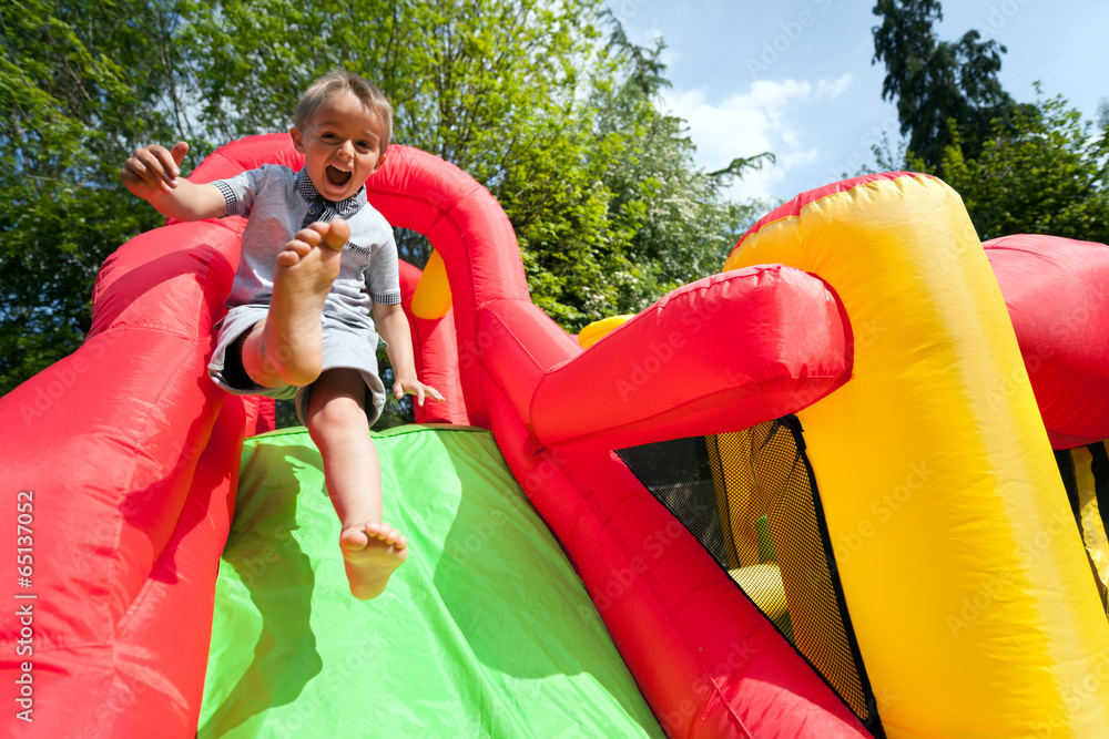Naklejka premium Child on inflatable bouncy castle slide