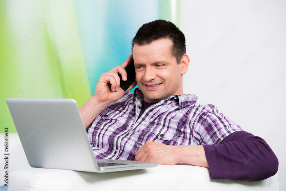 attraktiver mann telefoniert und schaut aufs laptop attraktiver mann telefoniert und schaut aufs laptop