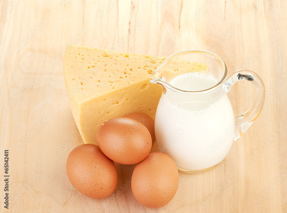 Big piece of cheese, glass jug with milk Big piece of cheese, glass jug with milk