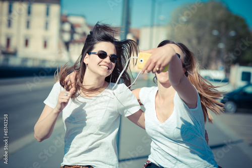 two beautiful young women using smart phone selfie