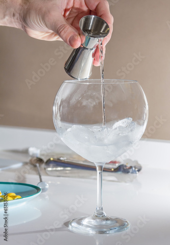 Barman pouring drink to prepare gin tonic cocktail