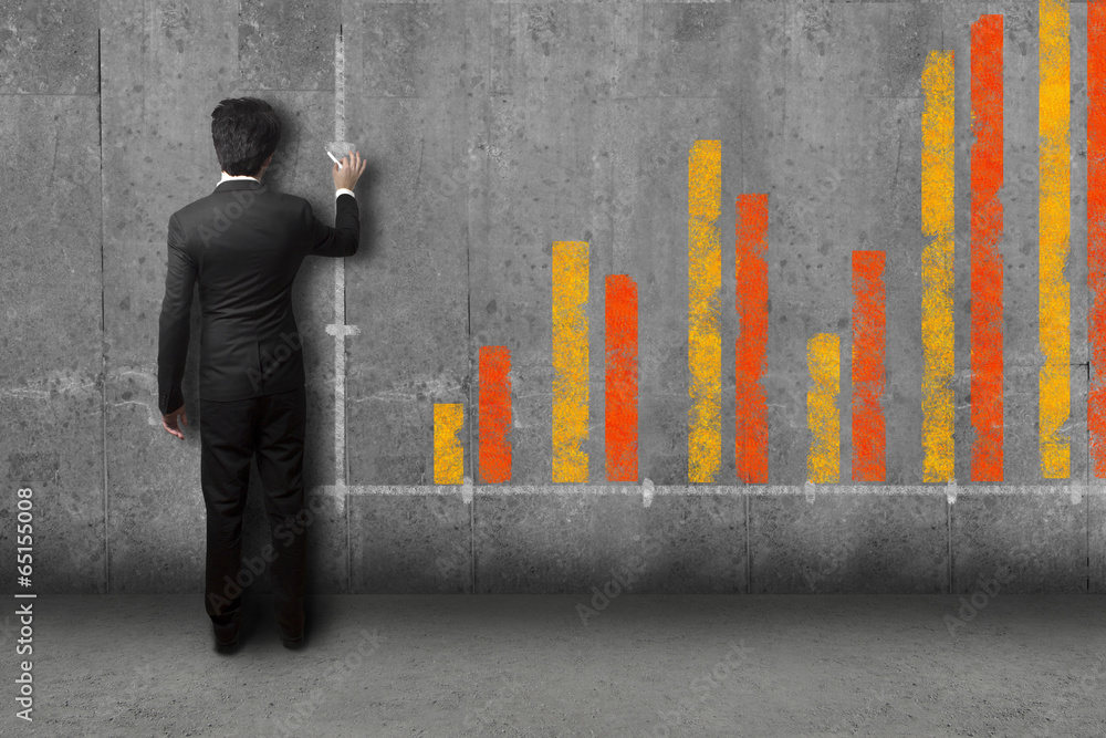 businessman in suite drawing a giant bar diagram on a stone wall businessman in suite drawing a giant bar diagram on a stone wall