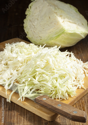 Chopped cabbage strips on a cutting board and a head of cabbage.
