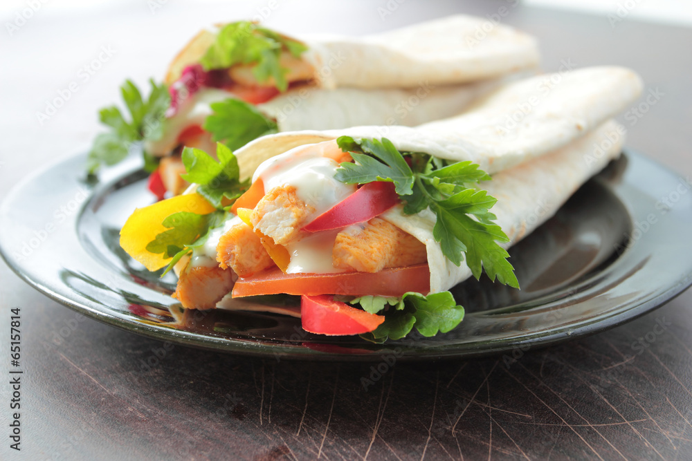 Tortilla wraps with chicken, vegetables and dressing on a plate
