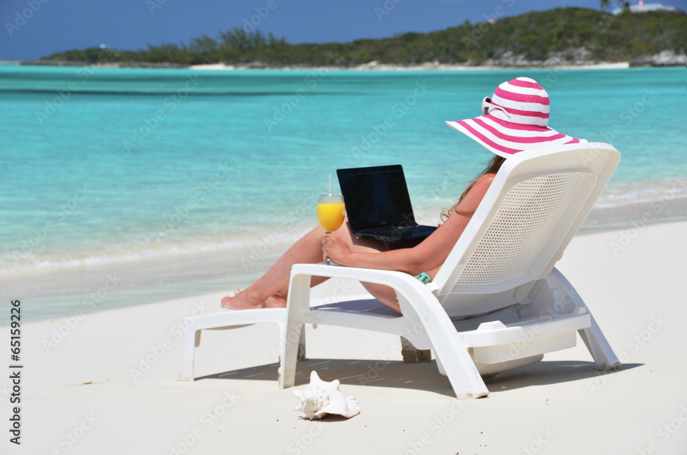 Girl with a laptop on the tropical beach. Exuma, Bahamas