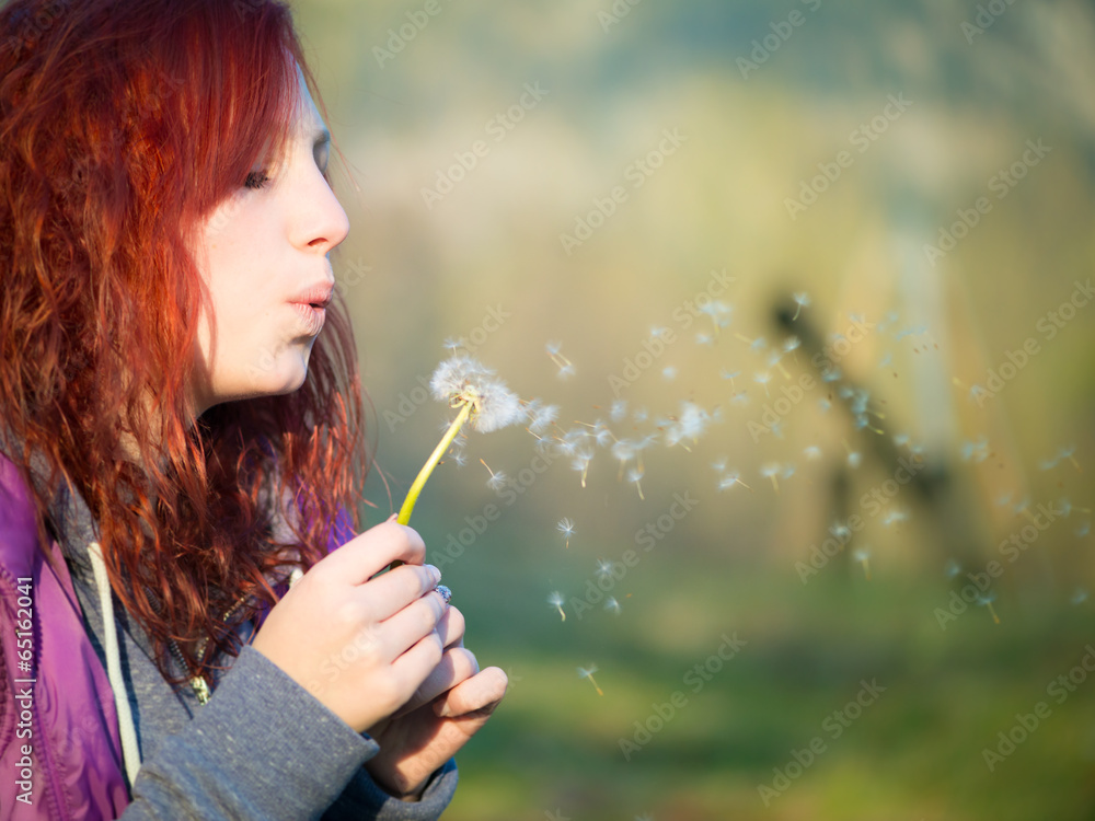 young teenager girl with red hairs blow to dandelion flower young teenager girl with red hairs blow to dandelion flower