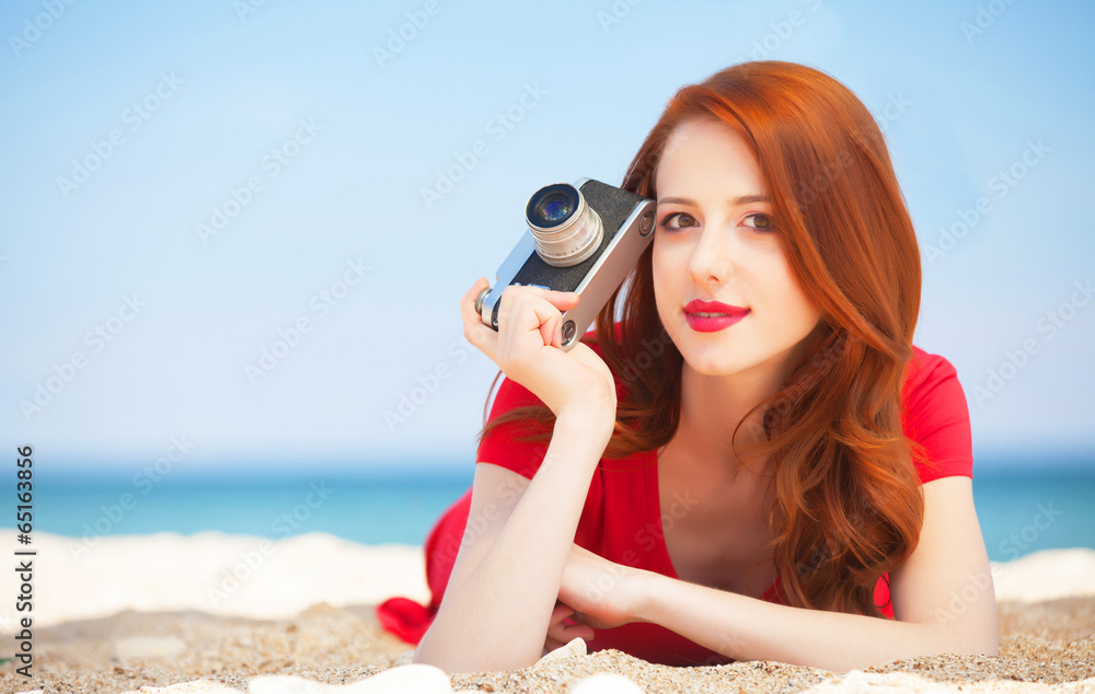 Redhead girl with camera on the beach