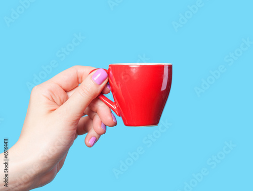Hand holding red cup on blue background