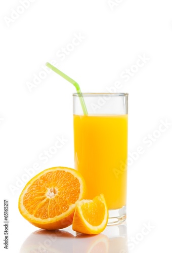 glass of orange juice with straw near half orange and slice