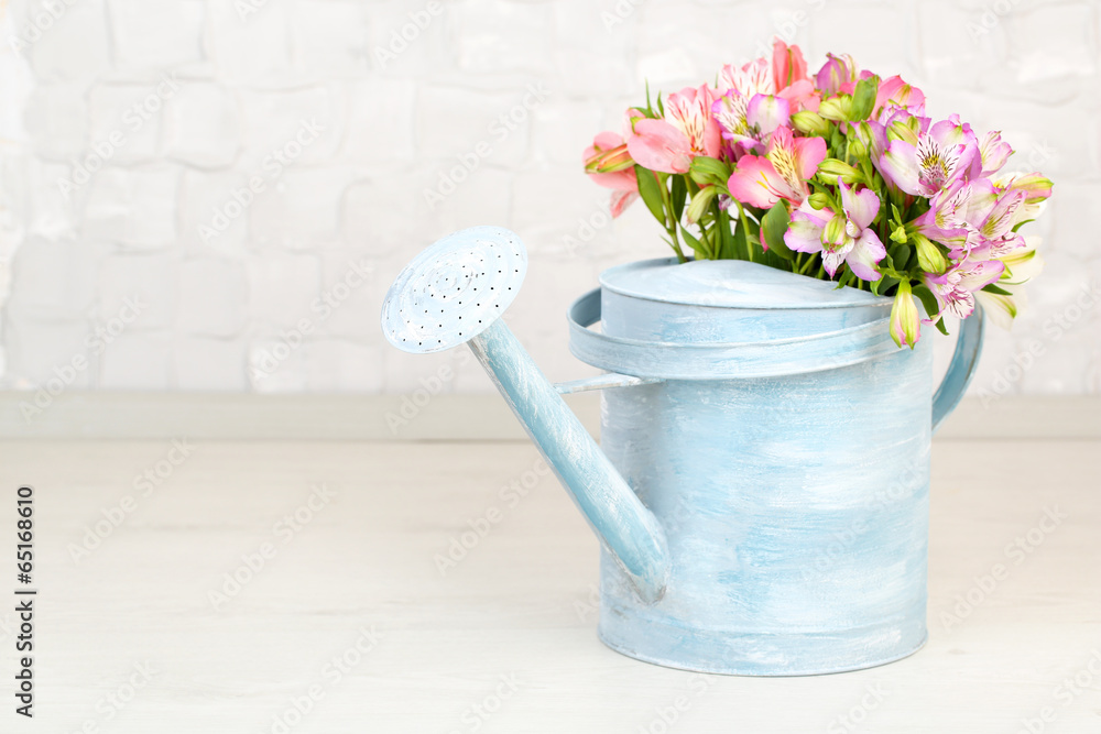 Fototapeta premium Beautiful bouquet of freesias in watering can in room