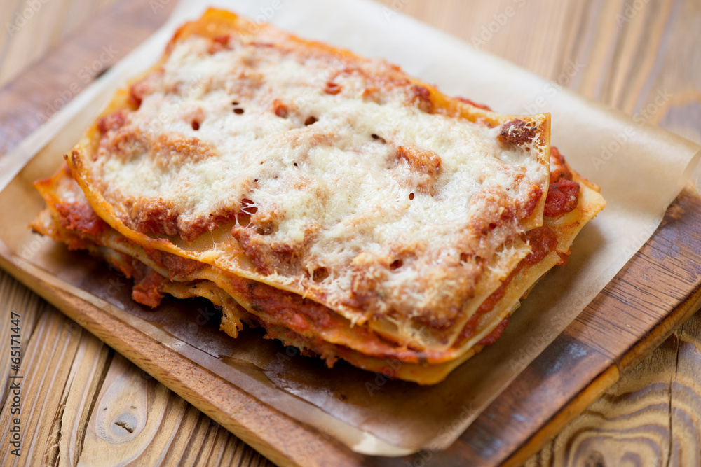 Lasagna bolognese on a rustic wooden cutting board