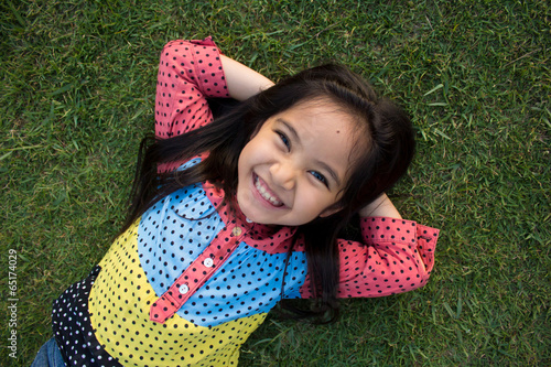 Картината върху платно Little Asian child laying down on the lawn
