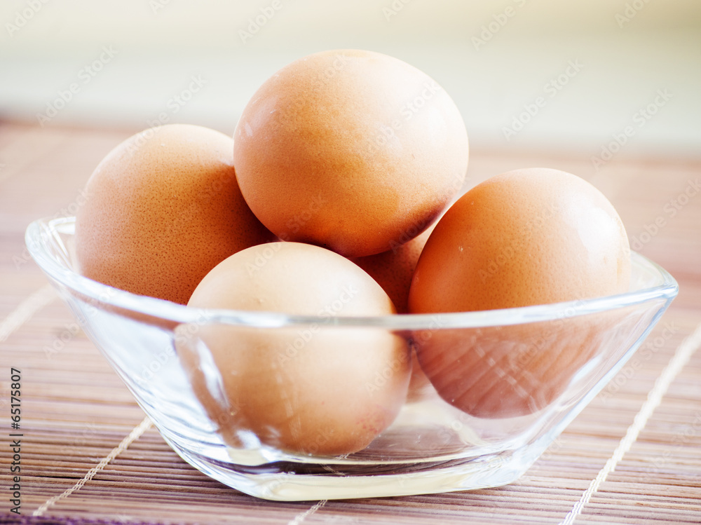 eggs close up in glass bowl on wooden background eggs close up in glass bowl on wooden background