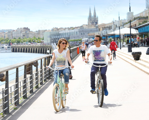 Cheerful couple riding bikes by sunny day