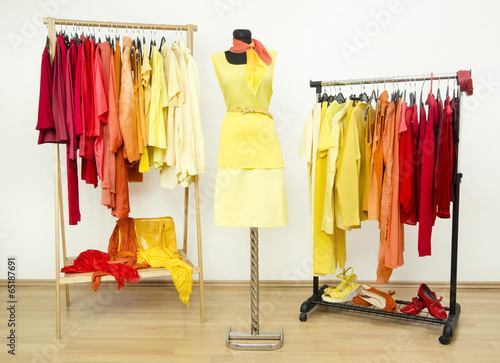 Wardrobe with yellow,orange and red clothes on hangers and dummy