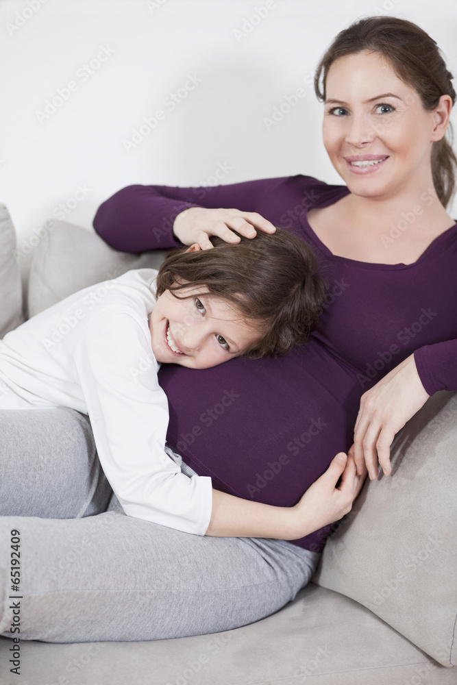 Tochter ( 8-9) umarmt schwangere Mutter 