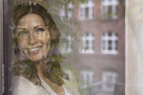 Deutschland,Frau schaut aus dem Fenster und lächelnd