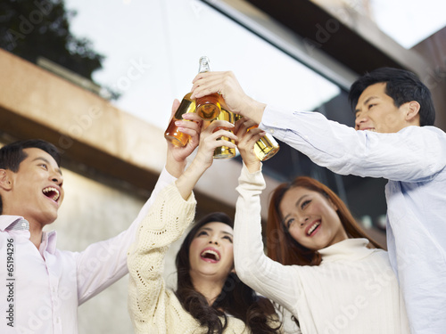 Photography asian young adult friends raising beer bottles for a toast
