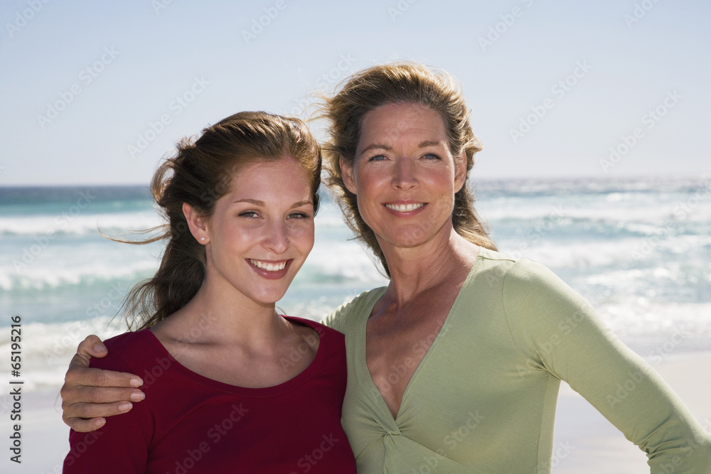 Fototapeta premium Mutter und Tochter stehen am Strand,lächelnd,Porträt