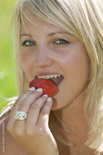  Junge Frau isst Erdbeere , Portrait