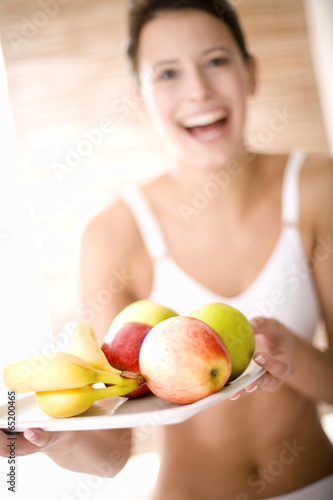 Junge Frau hält Tablett mit Obst, lächelnd