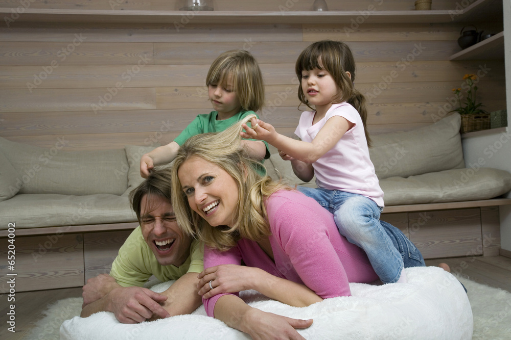 Familie im Wohnzimmer,die Kinder auf den Hals der Eltern sitzen,Lächeln,Portrait