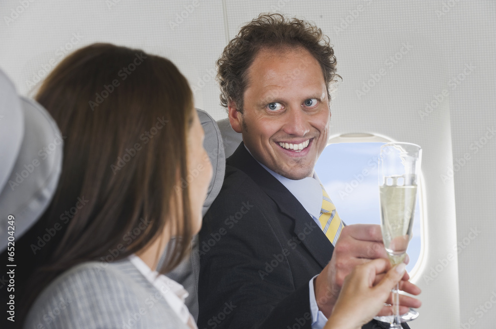Deutschland,Bayern,München,Kaufmann und Frau mit Champagner in der Business Class Flugzeugkabine,lächelnd Deutschland,Bayern,München,Kaufmann und Frau mit Champagner in der Business Class Flugzeugkabine,lächelnd