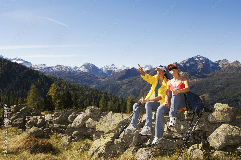 Fototapeta premium Zwei Frauen in den Bergen, die sitzen auf Felsen