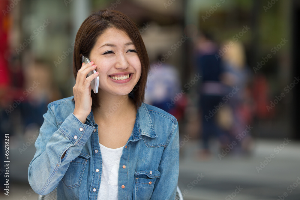 Young Asian woman in a city talking on cellphone