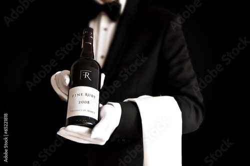 Fotografía Waiter in tuxedo holding a bottel of red wine