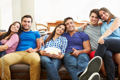 Group Of Friends Sitting On Sofa Watching TV Together