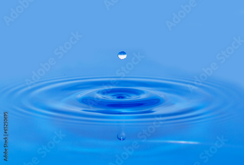 a drop of water falling in blue water. macro