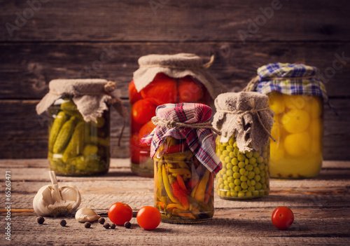 Preserved and fresh vegetables on wooden background