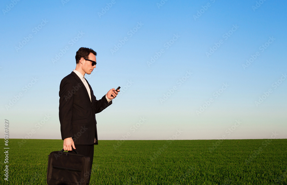 businessman with smartphone in green field businessman with smartphone in green field