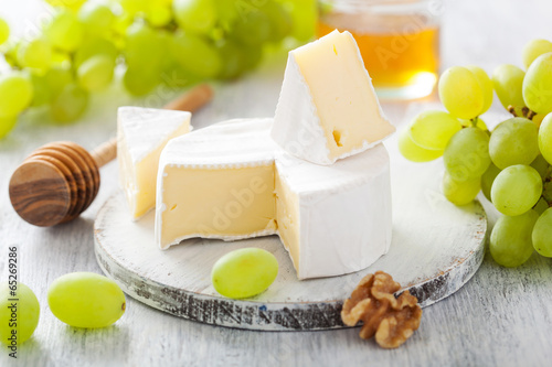 camembert cheese with grapes, honey and nuts on wooden backgroun