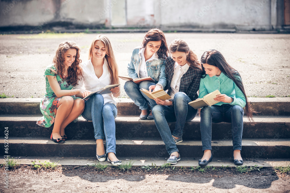 Group of students sitting with a books on street Group of students sitting with a books on street