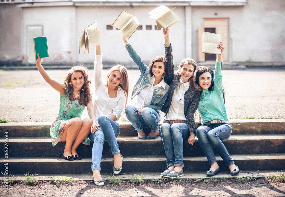 Fototapeta premium Group of students sitting with a books on street
