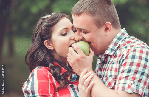 young pregnant woman eating apple with the husband outdoor