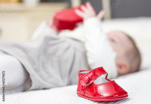 Baby red shoes and babe playing on the background