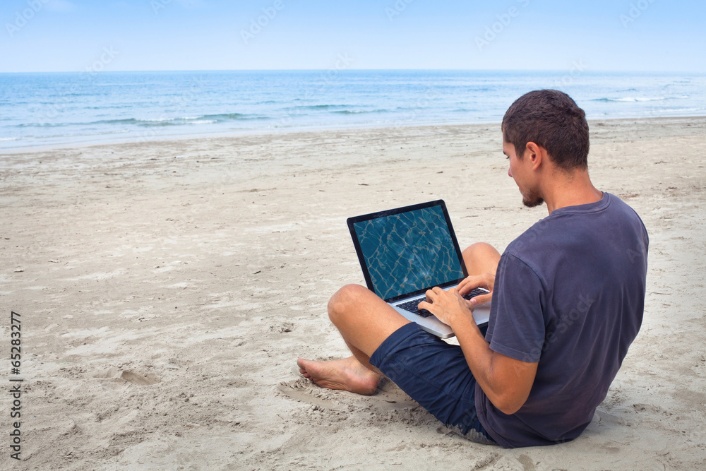 man using computer with wireless internet on the beach