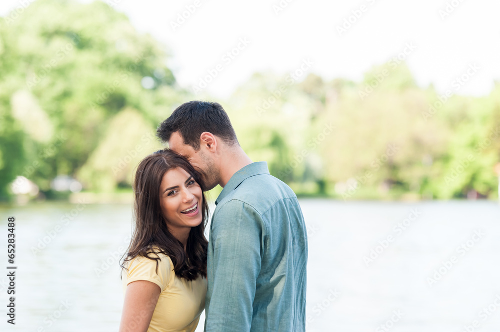Naklejka premium Young couple outdoors, near lake. hugging and havving a good time