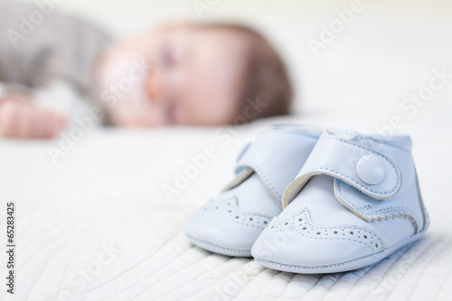 Baby blue shoes and babe sleeping on background photo