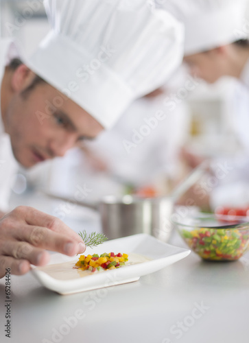closeup on chef garnishing a plate