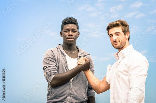 Afroamerican and caucasian men shaking hands against racism