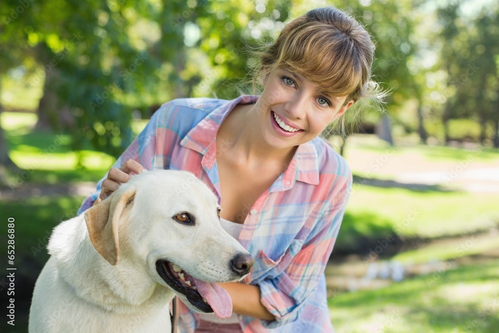 Pretty smiling blonde posing with her labrador in the park Pretty smiling blonde posing with her labrador in the park