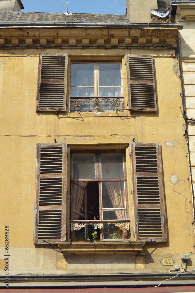 Facade of a decayed apartment with open window shutters