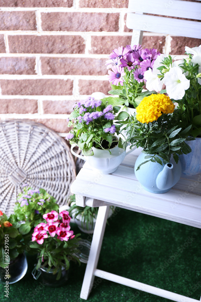 Flowers in  decorative pots on chair, on bricks background