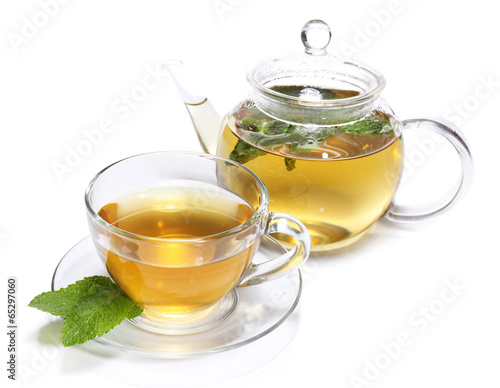 Composition of fresh mint tea in glass cup and teapot and brown